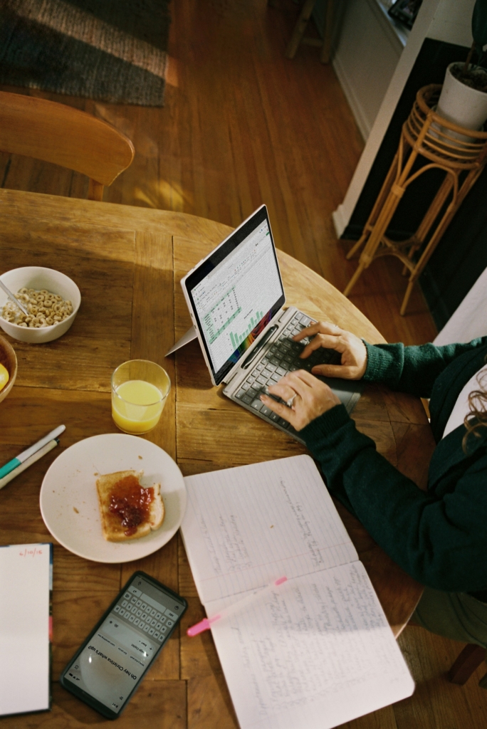 Mujer trabajando en su laptop mientras desayuna