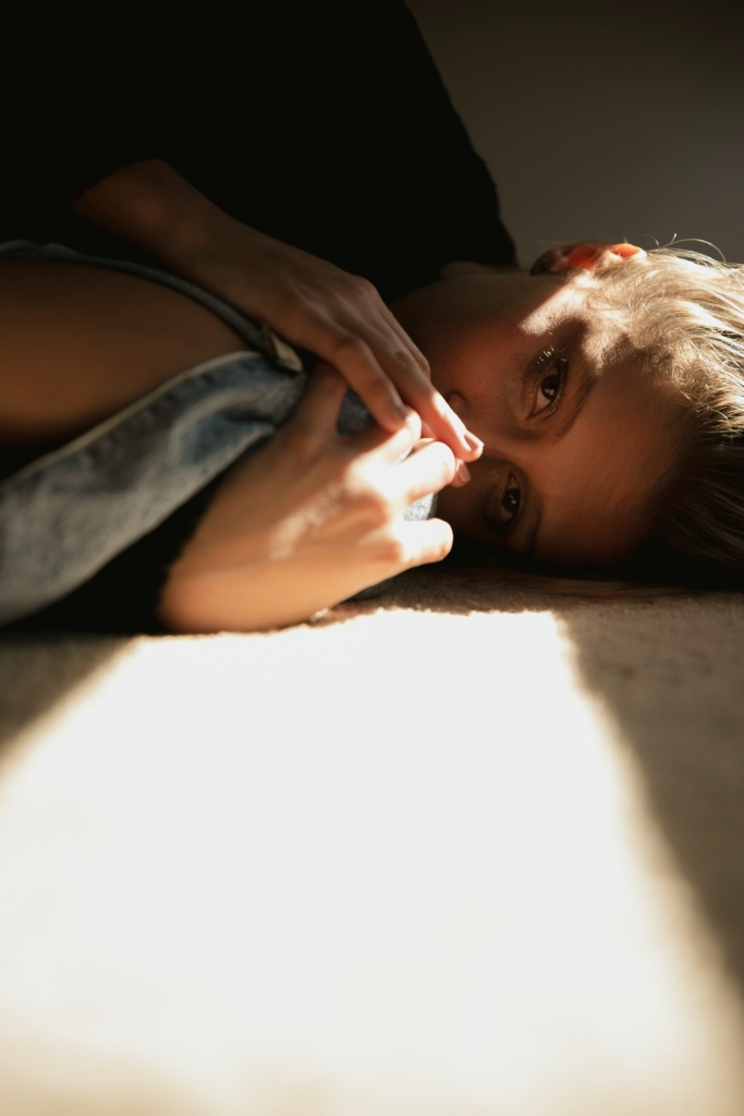 Fiatal nő a padlószőnyegen fekszik, a nap süti az arcát