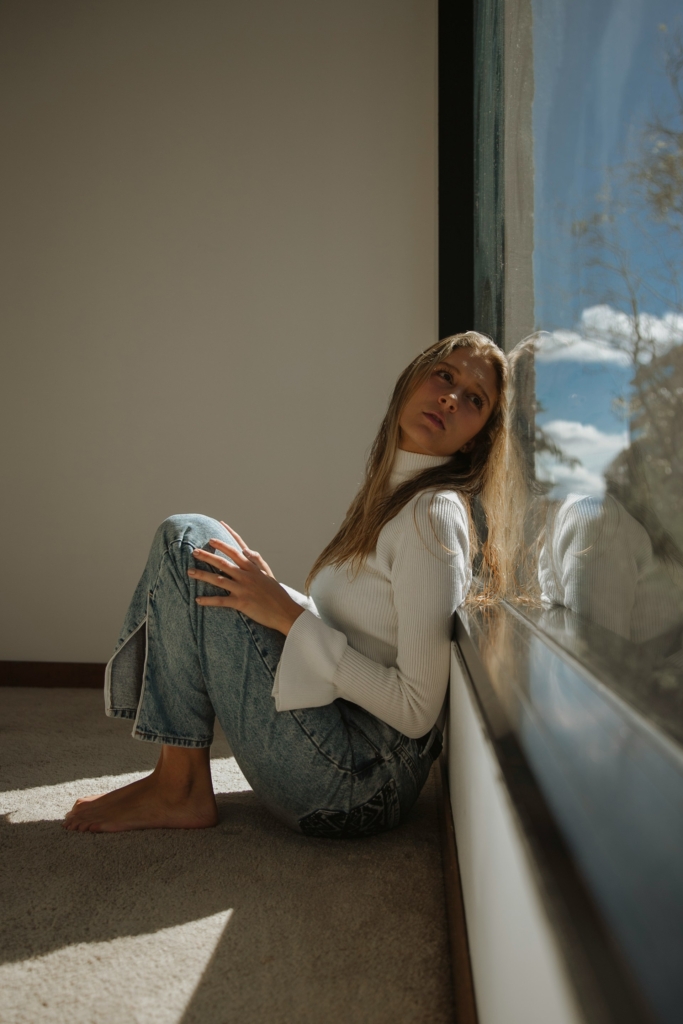 Fiatal nő vágyakozón az ablaknak dőlve