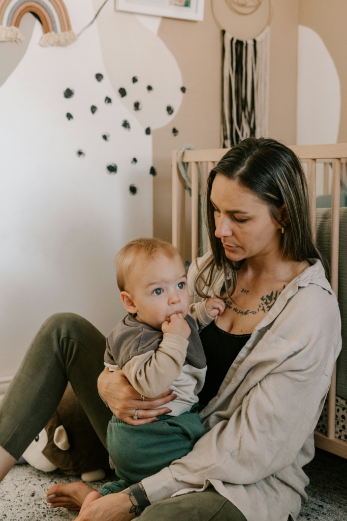 Anyuka a kiságy mellett ül a gyermekével