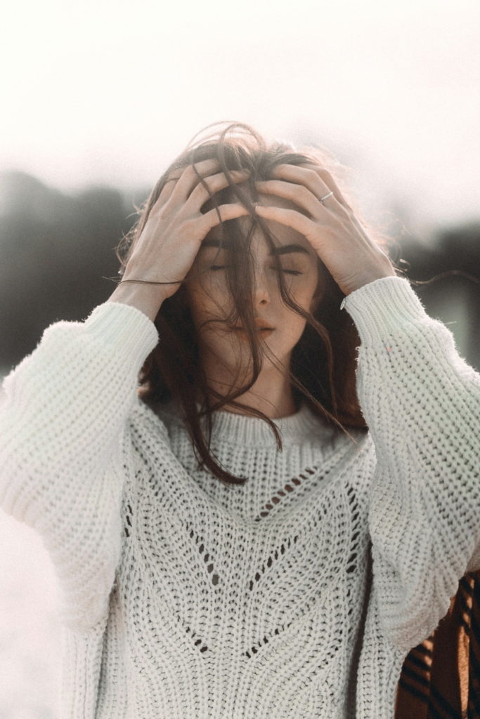 Nő a szabadban, behunyt szemmel, kezeit a homlokához emeli