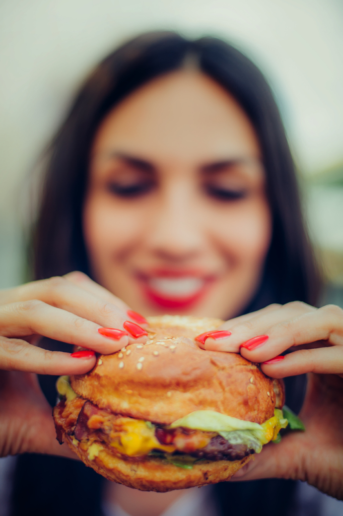 Boldog nő egy nagy hamburgerrel a kezében