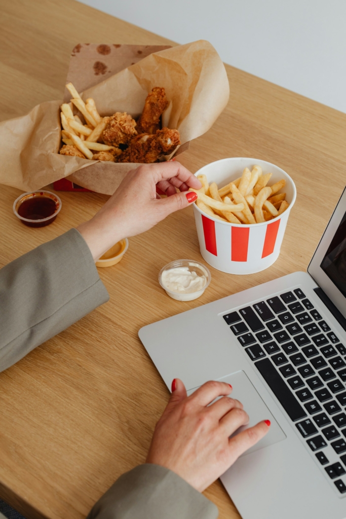 Nő laptopozás közben KFC menüt eszik