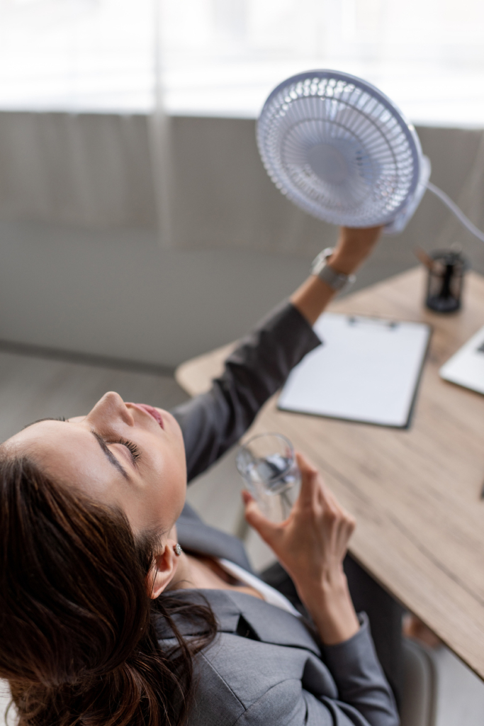 Nő egy ventilátorral hűsíti magát