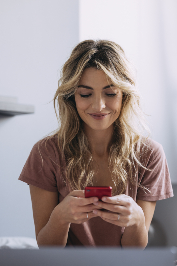 Mosolygós nő a telefonján üzenetet ír