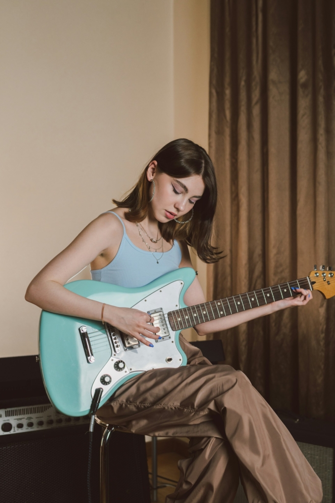 Fiatal lány elektromos gitáron játszik