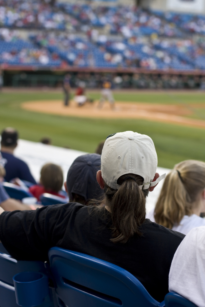 Nő ül egy baseball meccsen a lelátón