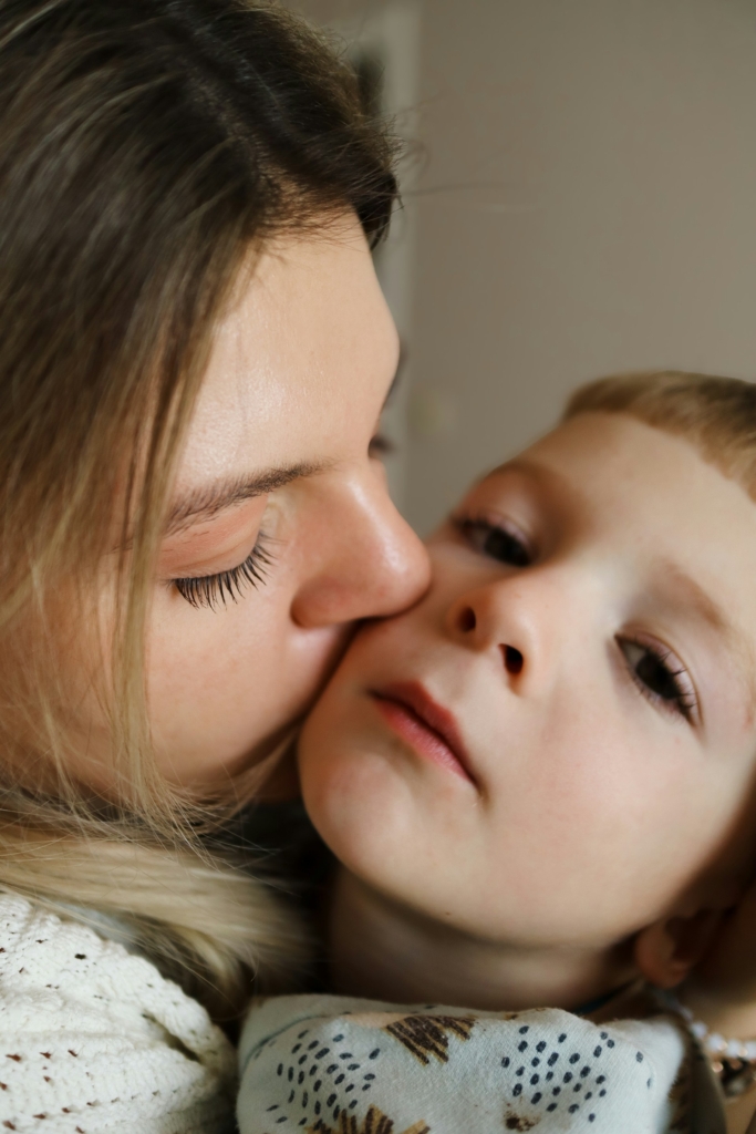 Közeli kép, ahogy az anyuka megpuszilja a kislánya arcát