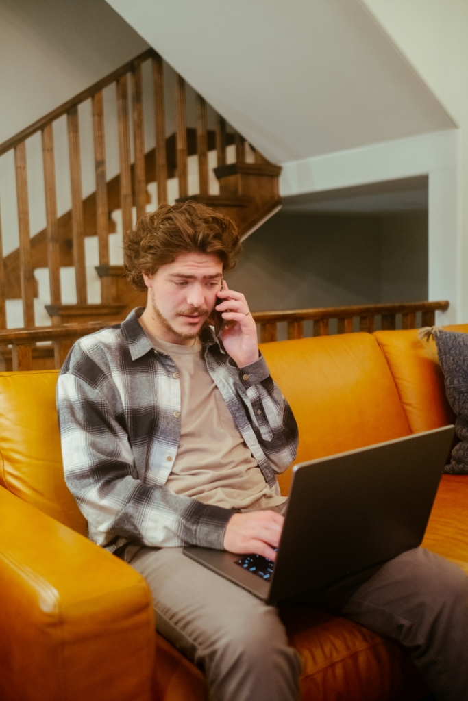Férfi telefonál, közben a laptopján néz valamit