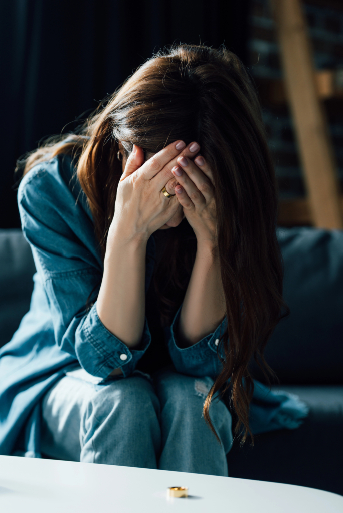 Depressziós nő a tenyerébe temeti az arcát, lehúzva hever előtte a karikagyűrűje