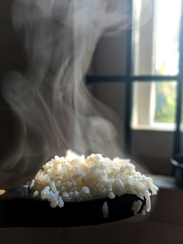 Gőzölgő főtt rizs egy fakanálon