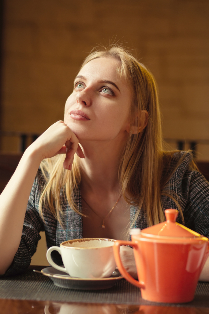 Szőke nő elgondolkodva egy csésze tea mellett