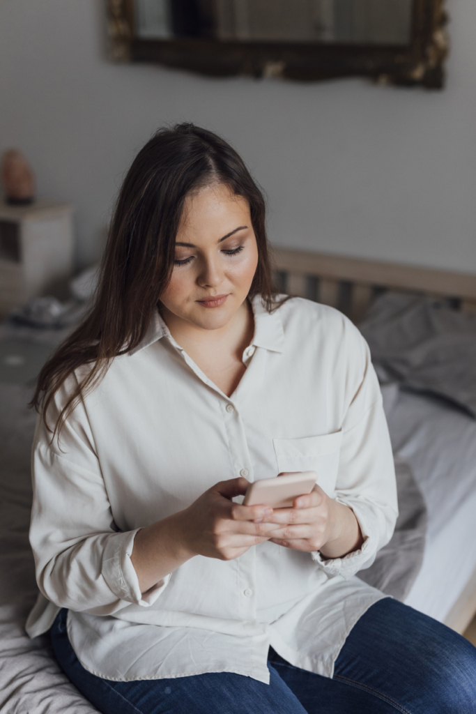 Plus size nő szomorúan nézi a telefonját