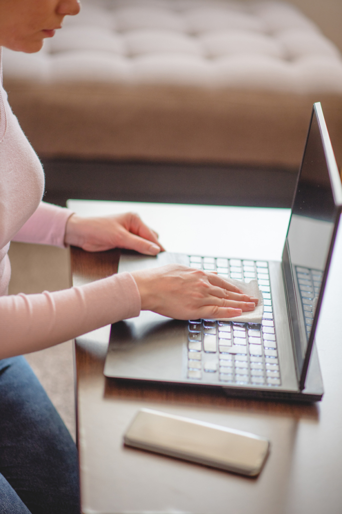 Nő nedves kendővel tisztítja a laptop billentyűzetét