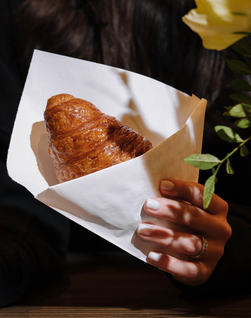 Nő egy croissont tart a kezében