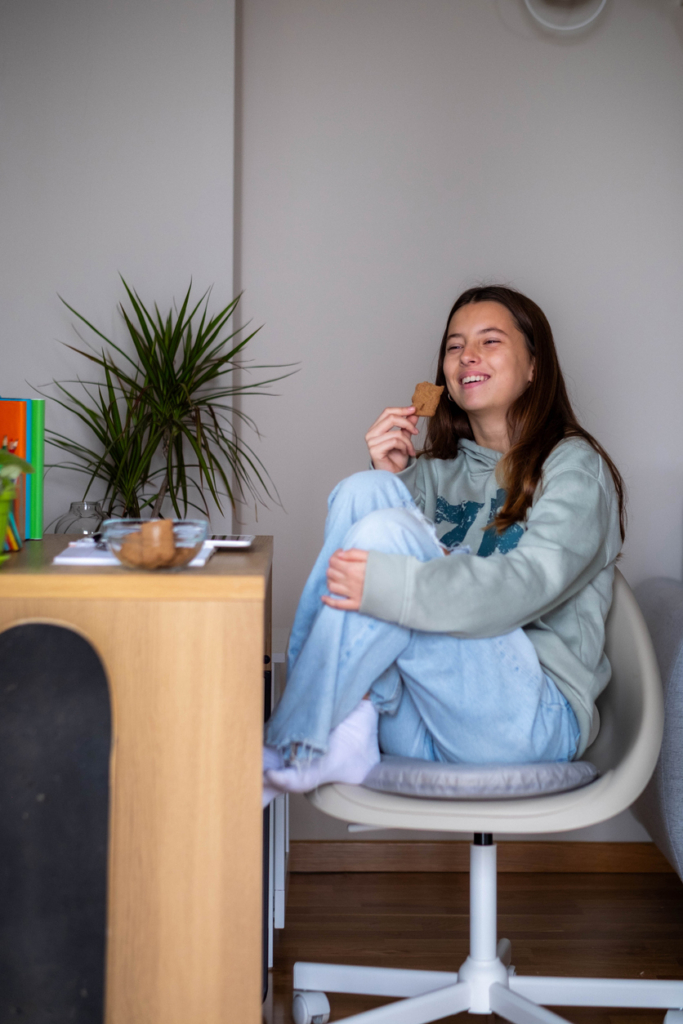 Fiatal lány kekszet eszik az íróasztalánál