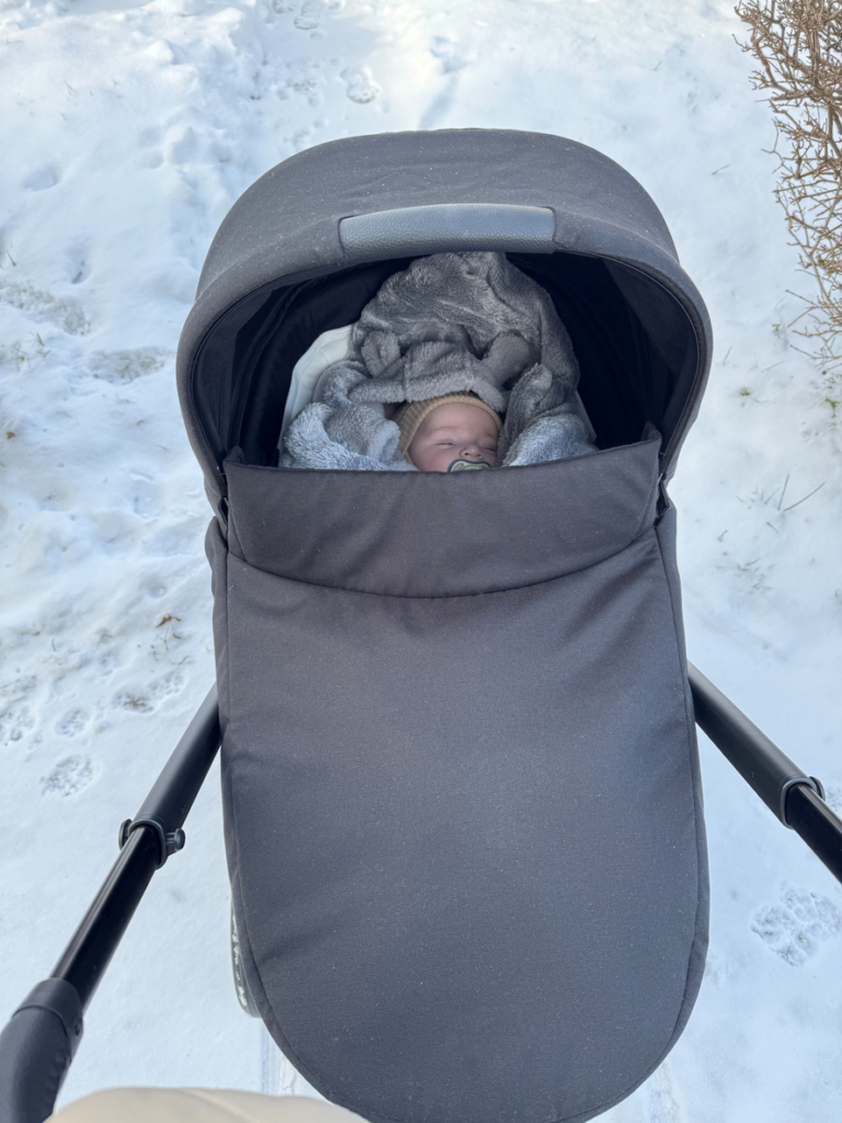 Csecsemő alszik a téli hidegben kint a babakocsiban