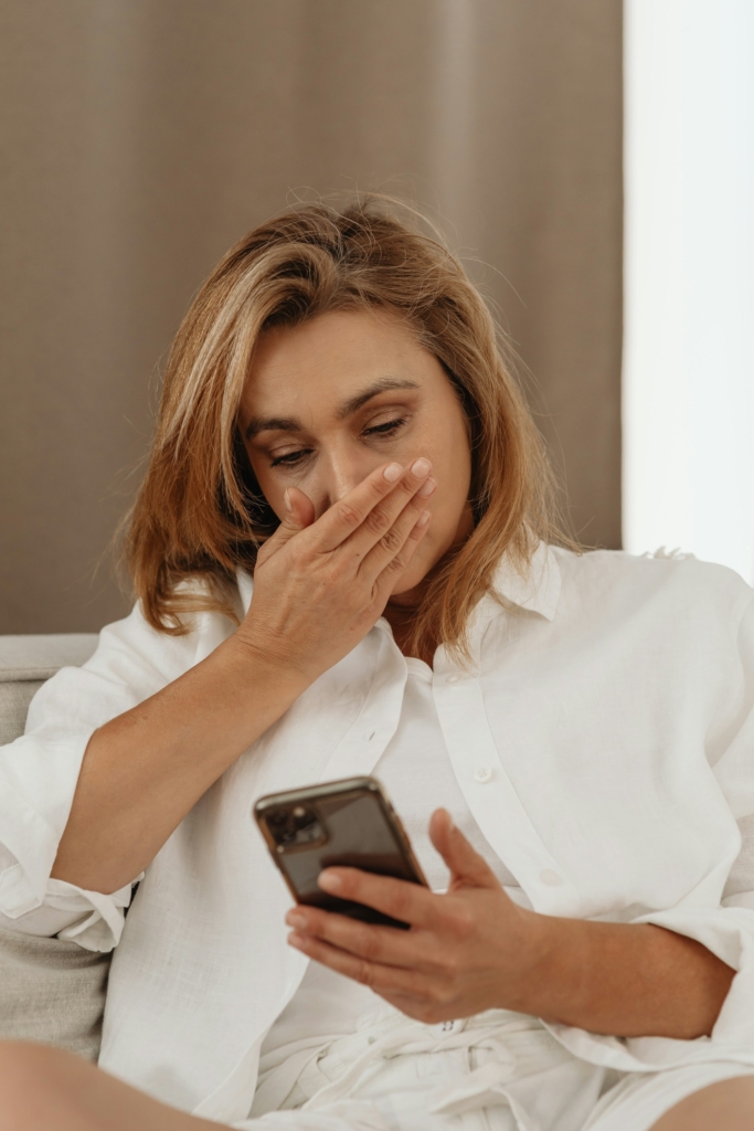 Nő meglepetten olvassa a telefonját