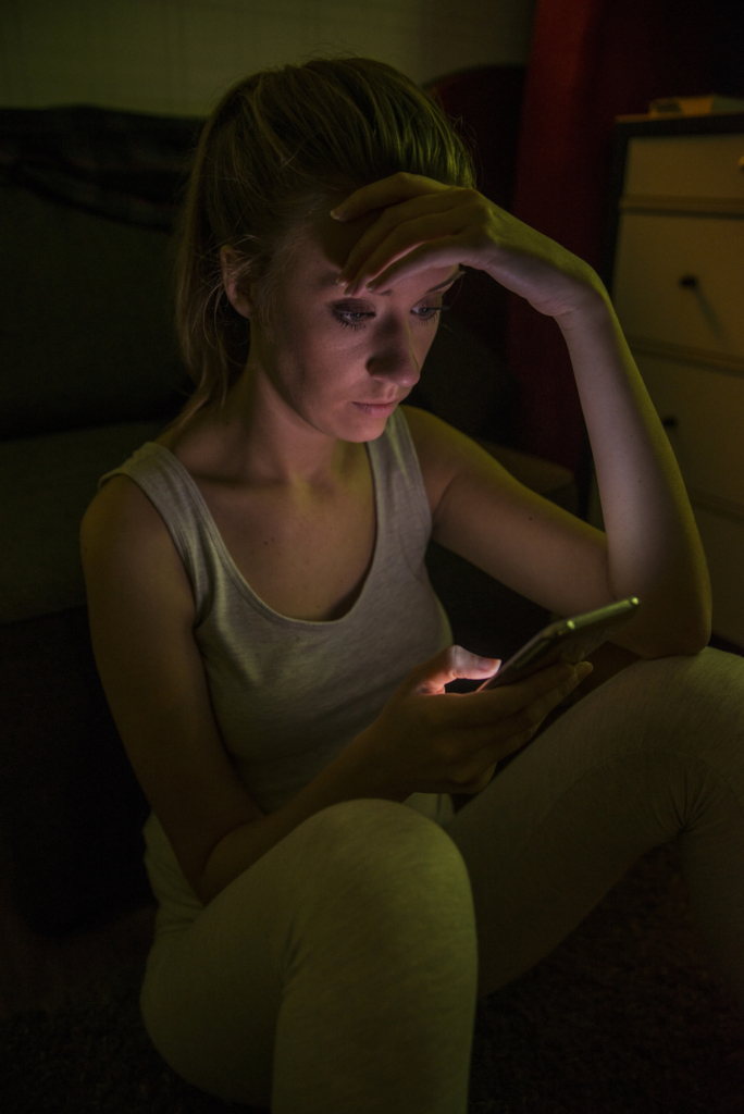 Nő este a sötétben görgeti a telefonját