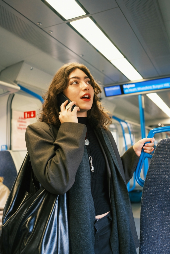 Nő állva telefonál a buszon