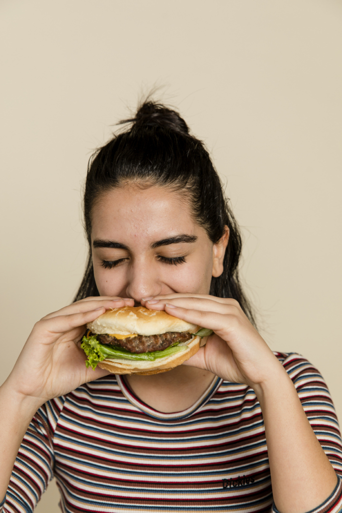 Nő beleharap egy nagy hamburgerbe