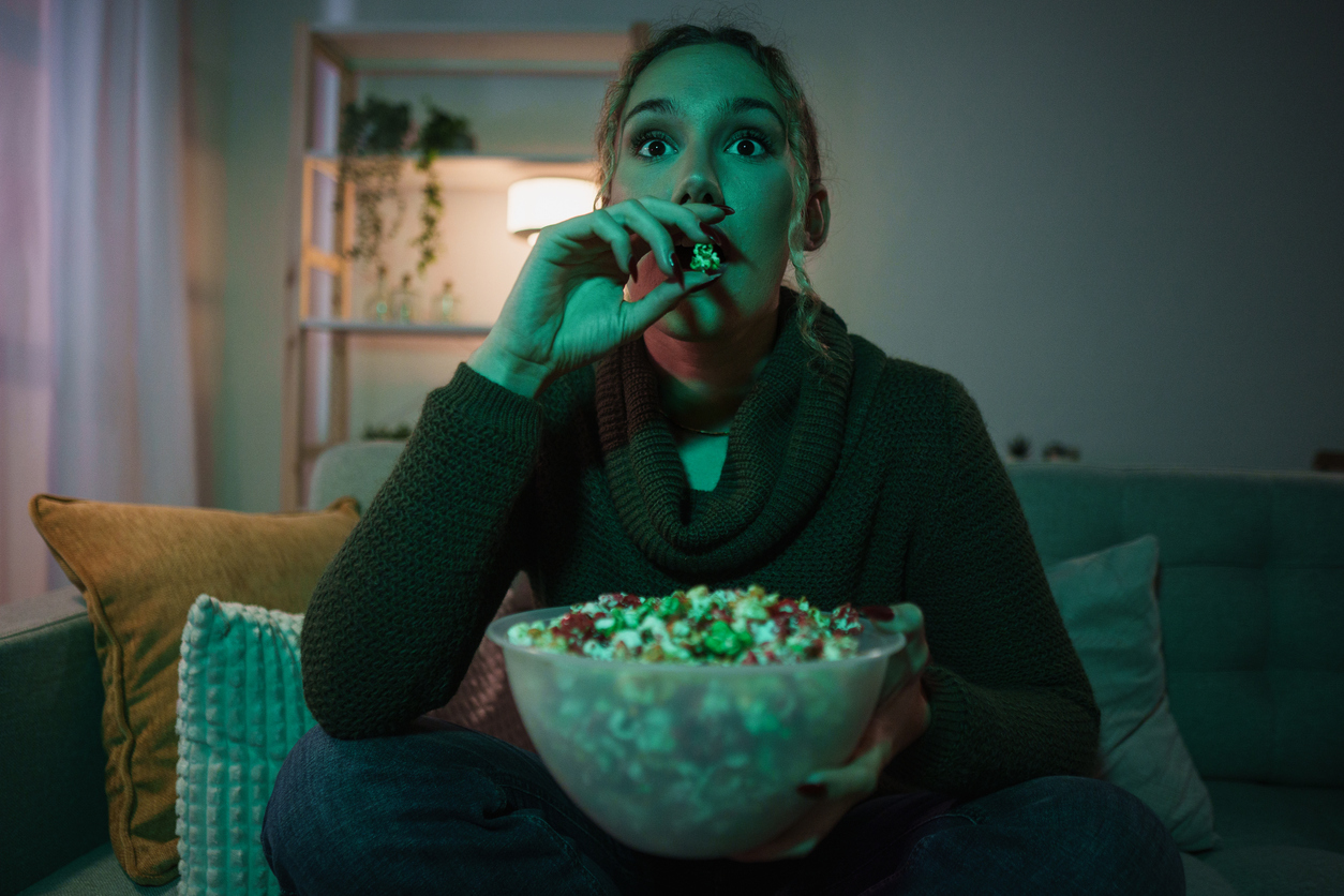 Megdöbbent fiatal nő filmet néz és popcornt eszik