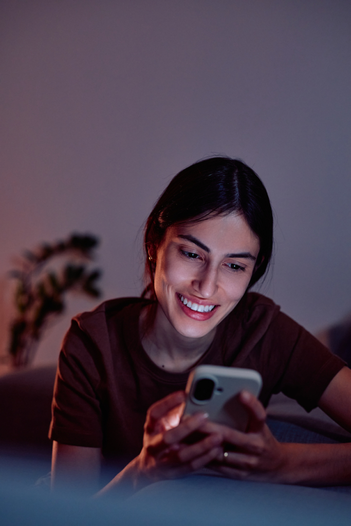 Mosolygós nő este üzenetet ír a telefonján