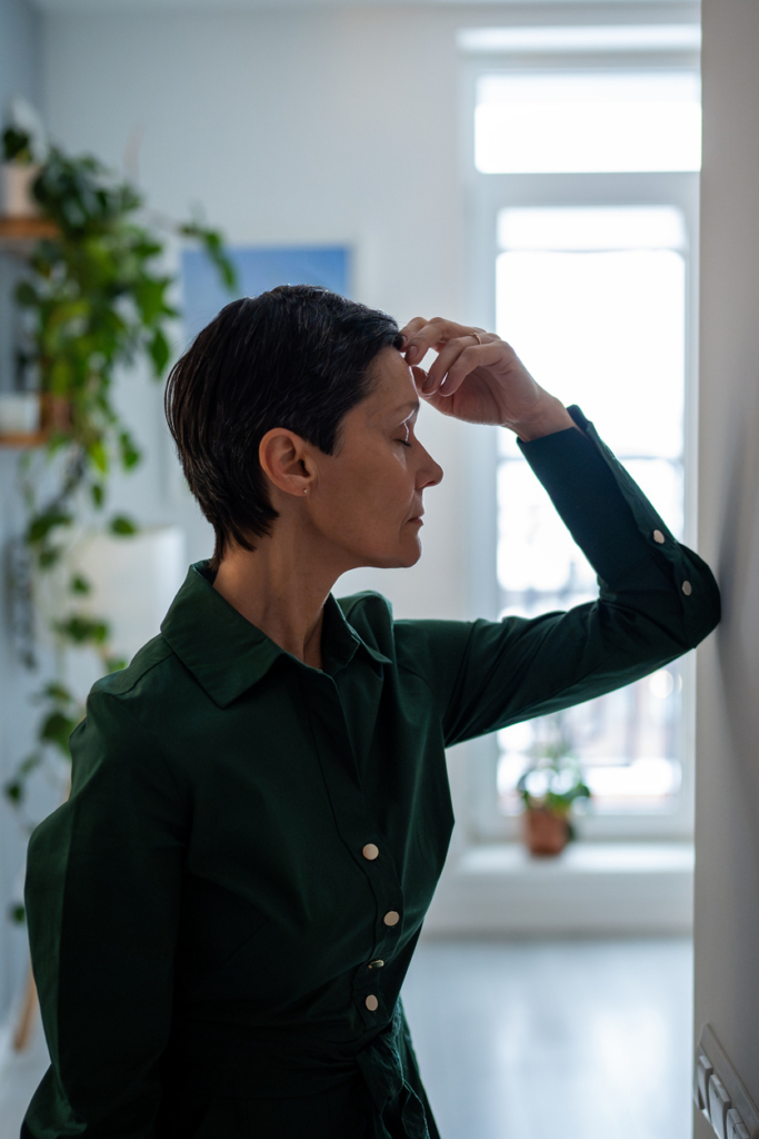 Stresszes nő az ajtófélfának könyököl