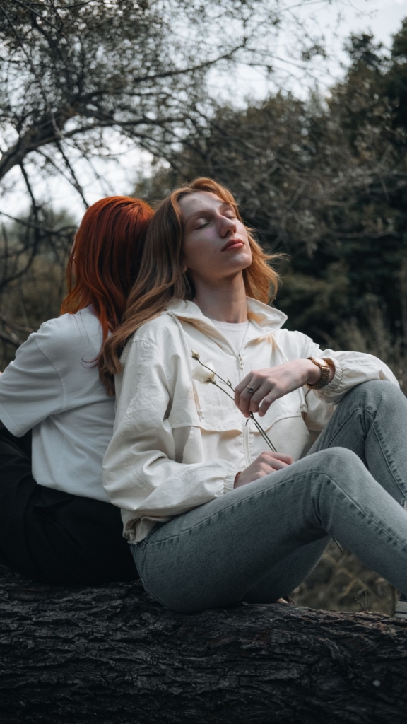 Két nő egymásnak háttal ül a szabadban