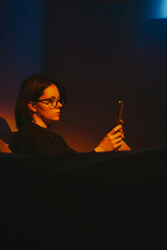 Nő a sötétben ül és nézi a telefonját