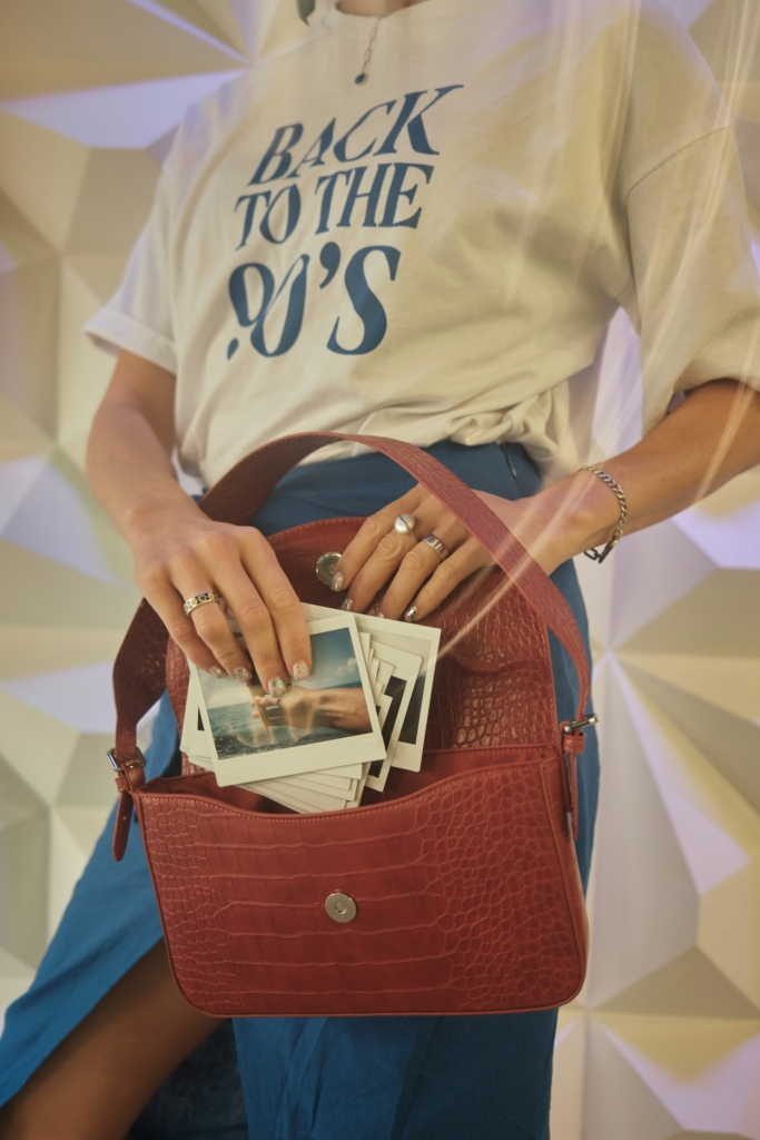 Nő polaroid képeket tesz a táskájába