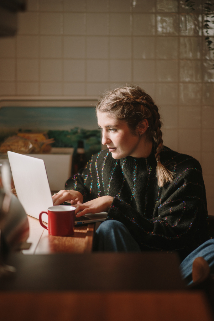 Nő a konyhában dolgozik a laptopján
