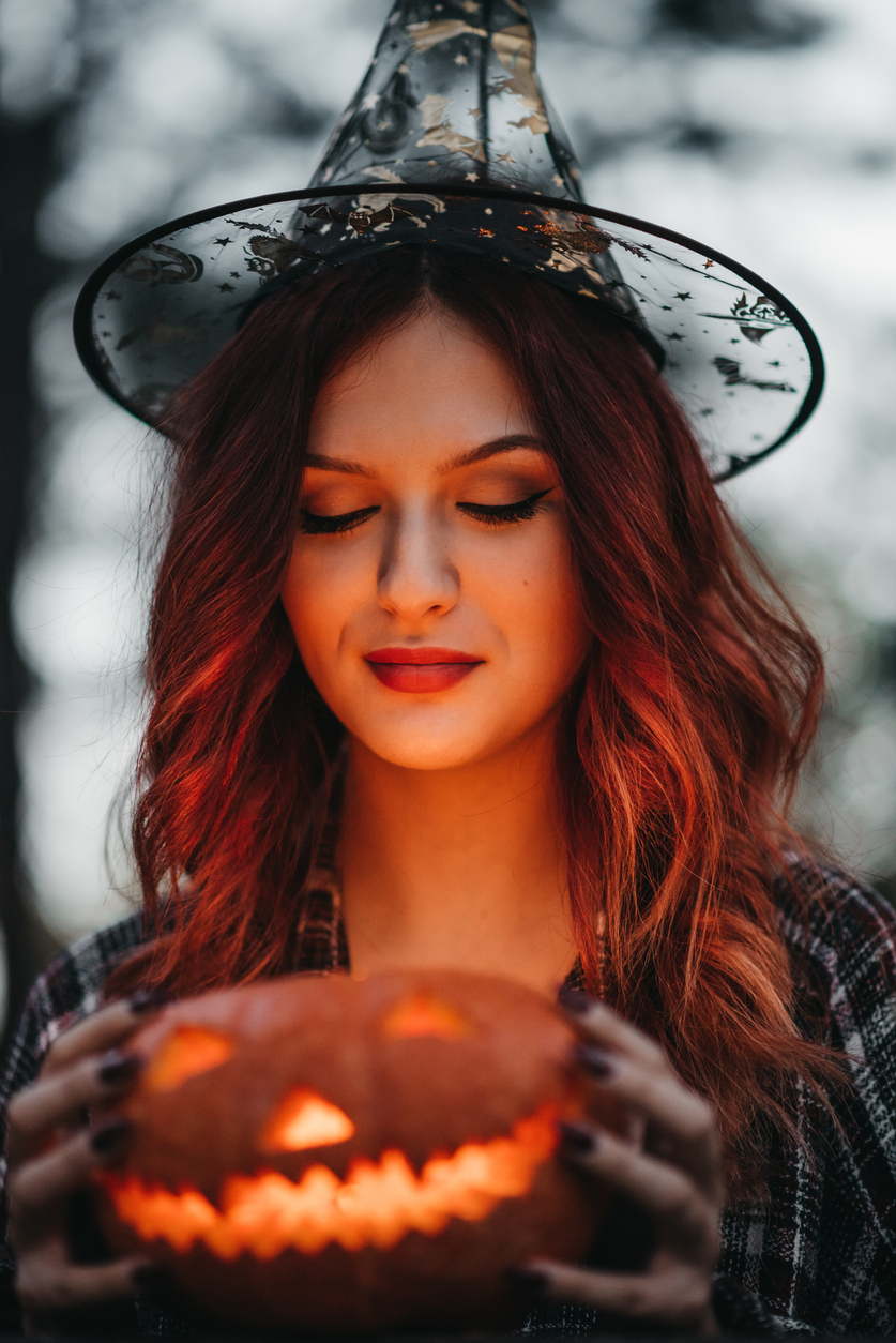Fiatal boszorkány Halloweeni tökkel a kezében