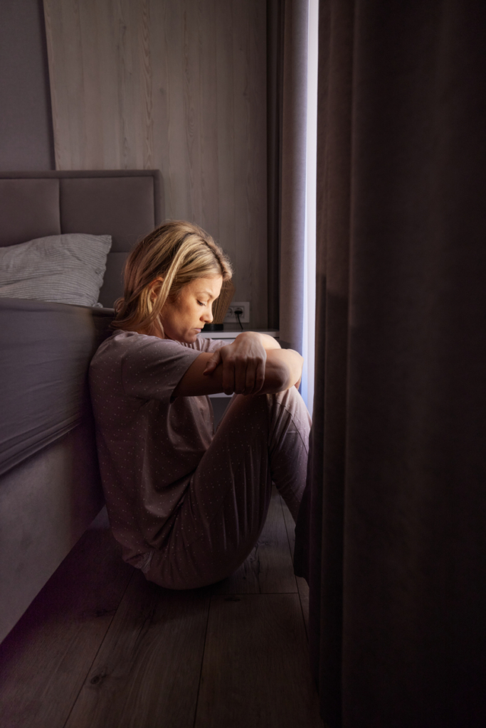 Depressziós nő ül a szobában a padlón