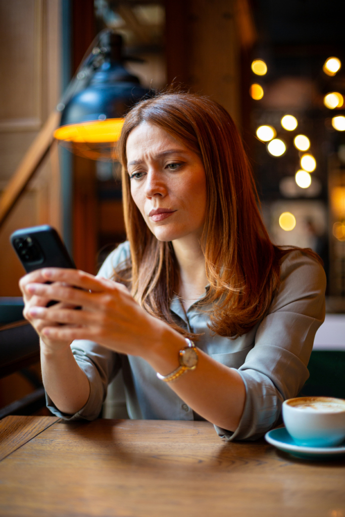 Nő a kávézóban telefonozik egyedül