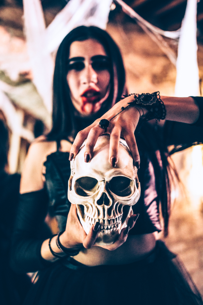 Halloweeni jelmezt viselő nő tart a kezében egy koponyát